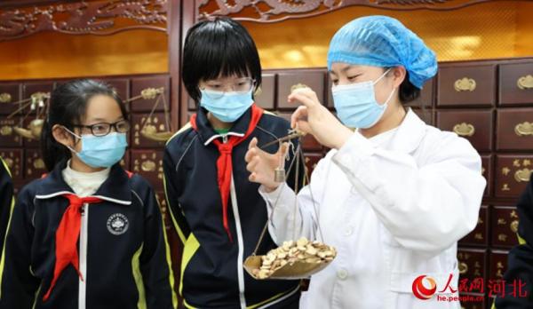 东光县中医院医务工作者为第三实验小学学生进行实际操作，演示如何准确称量中药材。朱林林摄